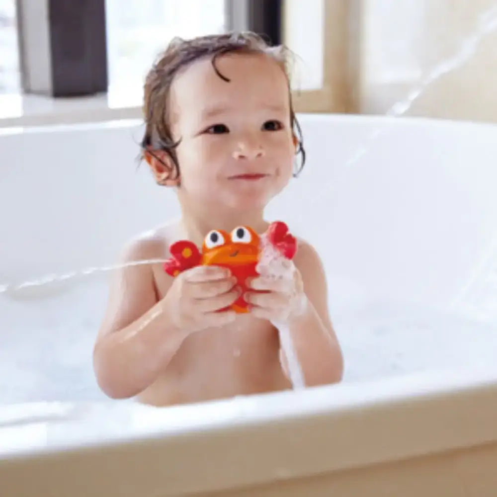 Niño jugando en la bañera con juguete Baño pez y cangrejo que dispara agua Hape
